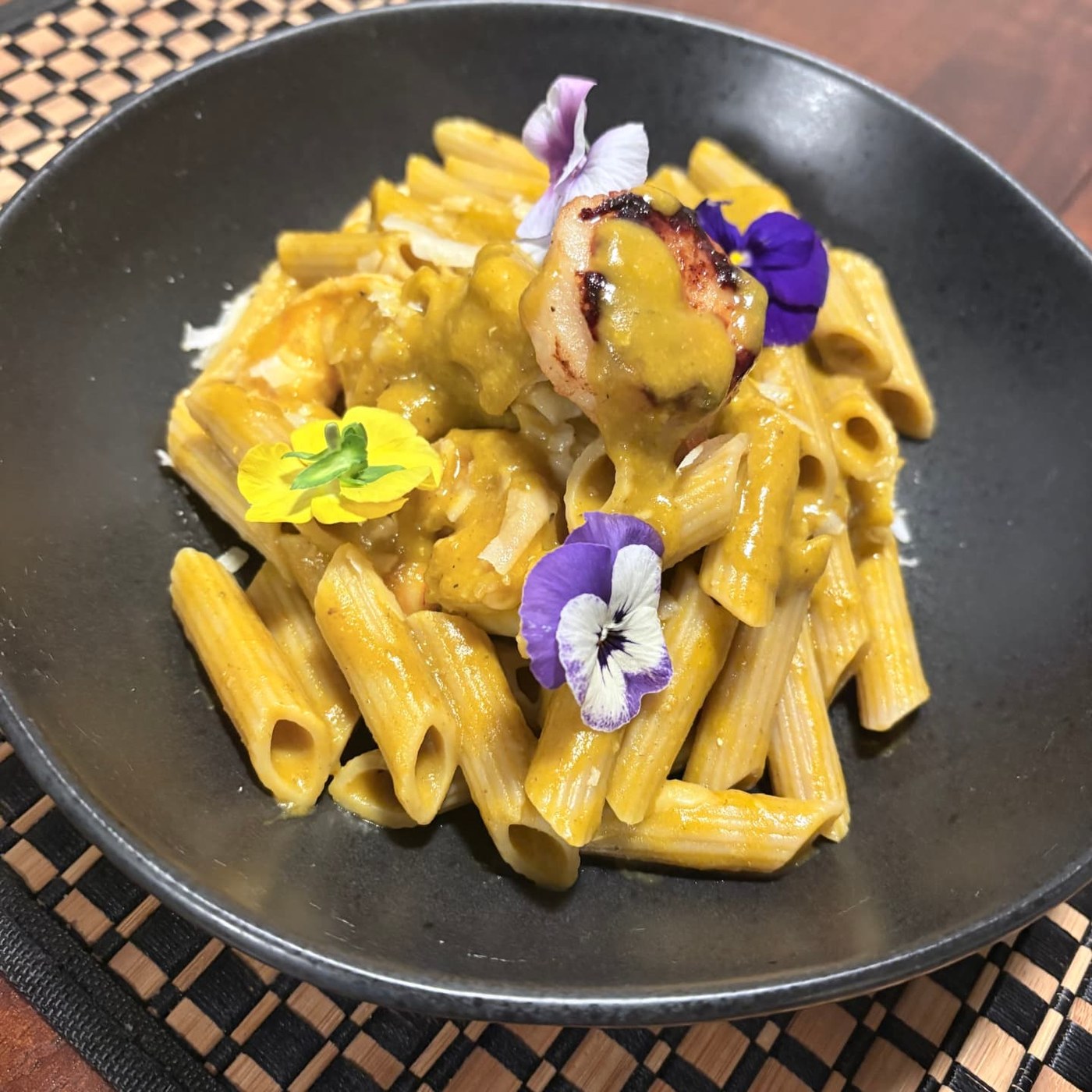 Curry penne pasta with shrimp and edible flowers